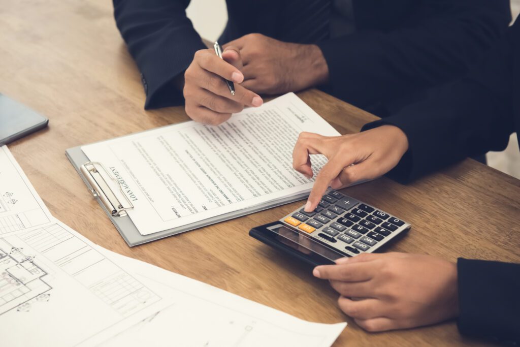 A person is using a calculator to calculate the cost of a home.