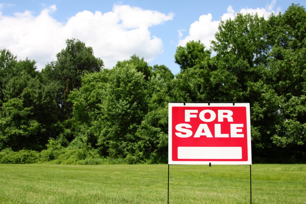 A for sale sign in front of some trees