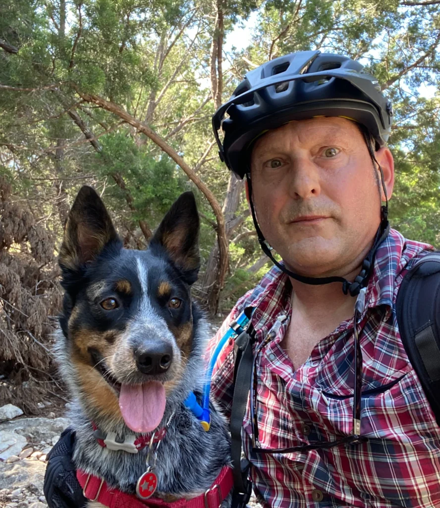 A man and his dog are hiking in the woods.