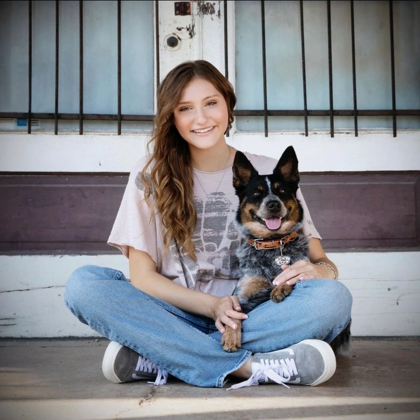 A woman sitting on the ground with her dog.